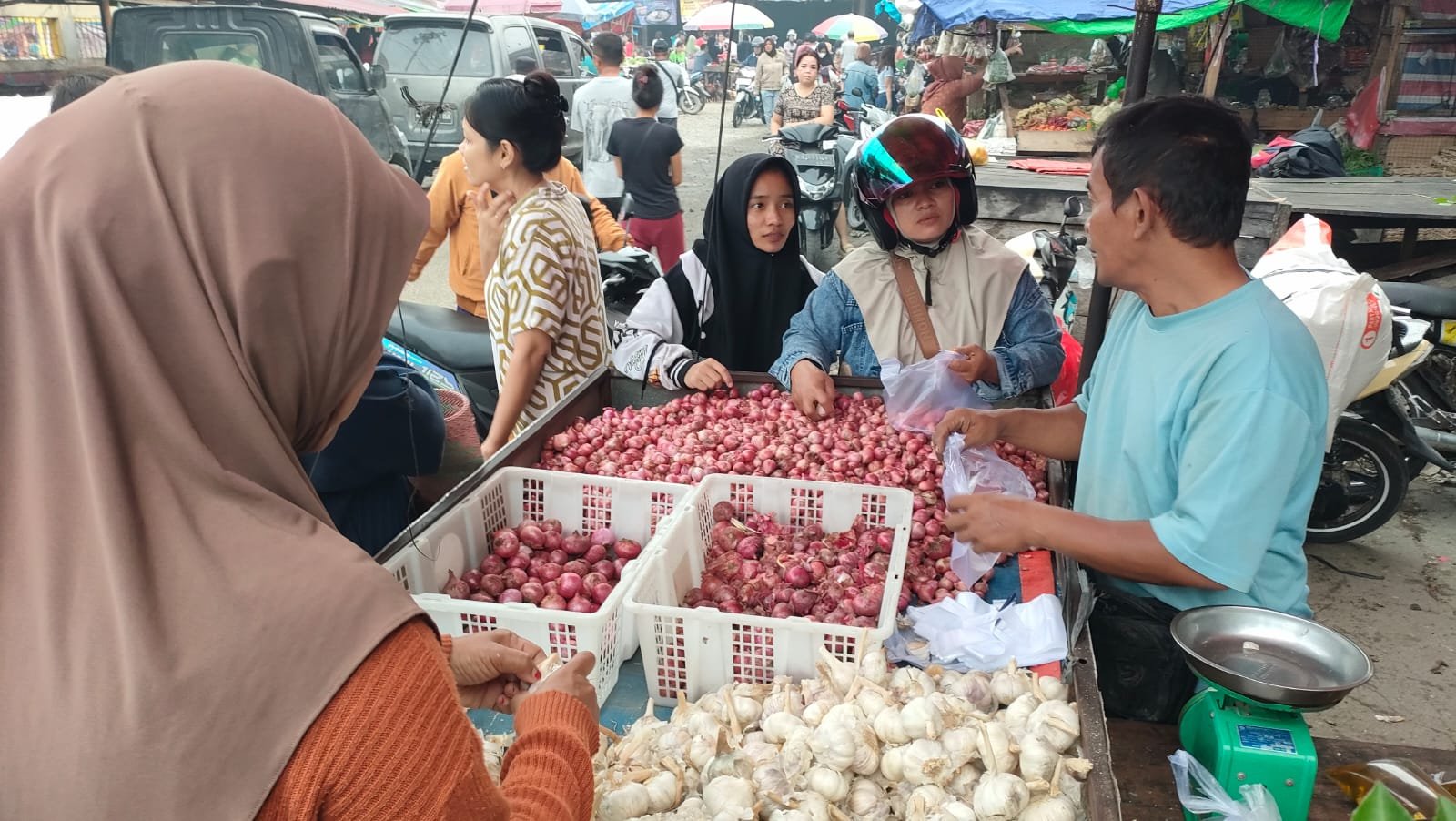 Imam Sukoco pedagang bawang di Pasar Pagi Sungai Pinyuh sedang melayani pembeli.