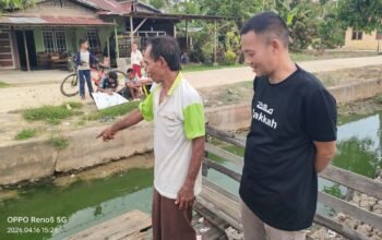 Saleh (baju putih), guru ngaji di Desa Sungai Batang, menyampaikan keluhannya kepada Kepala Desa Sungai Batang, Mahyus (baju hitam) terkait pencemaran lingkungan dari dapur MBG.