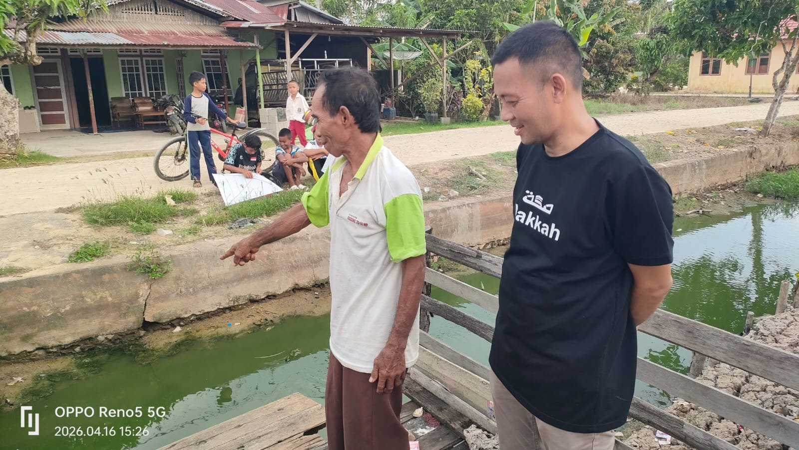 Saleh (baju putih), guru ngaji di Desa Sungai Batang, menyampaikan keluhannya kepada Kepala Desa Sungai Batang, Mahyus (baju hitam) terkait pencemaran lingkungan dari dapur MBG.
